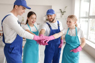 Bir grup hademe ofiste el ele tutuşuyor.