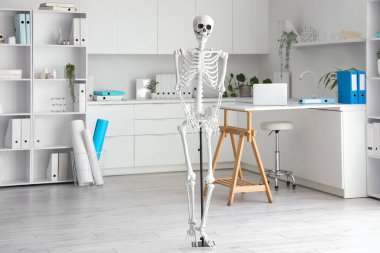 Masada insan iskeleti modeli ve modern dizüstü bilgisayarı olan hafif bir hastane.