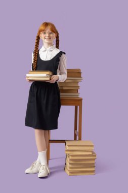 Leylak arkaplanıyla ilgili yığınla kitabı olan kızıl saçlı tatlı bir kız.