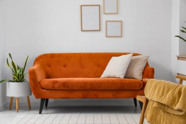 Beyaz duvarın yanında rahat kahverengi kanepesi olan modern oturma odası, yakın plan.