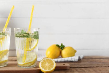 Bir bardak taze limonata, nane ve ahşap masada limon.