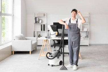 Ofisinde modern elektrik süpürgesi olan genç erkek hademe.