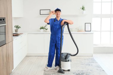Mutfakta modern elektrik süpürgesi olan genç bir erkek hademe.