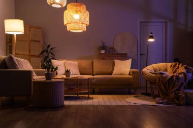 Şık oturma odasının içinde rahat gri koltuklar, sehpa ve geceleri parlayan lambalar.