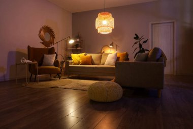 Şık oturma odasının içinde rahat gri koltuklar, koltuk ve akşamları parlayan lambalar