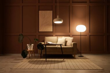 Şık oturma odasının içinde rahat bir kanepe, sehpa ve akşam lambaları var.