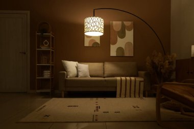 Şık oturma odasının içinde rahat bir kanepe, otlar ve akşamları parlayan lamba.