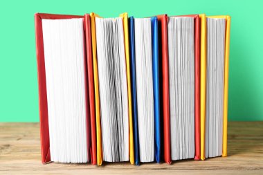 Ahşap masa üzerinde yeşil arka plana karşı renkli kitaplar dizisi