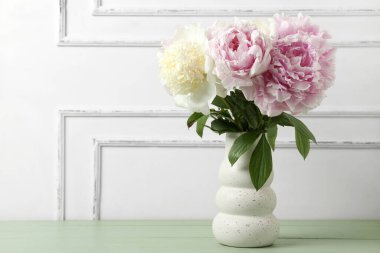 Yeşil ahşap masa üzerinde güzel şakayık çiçekleri olan vazo.