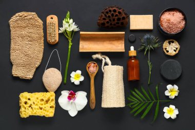 Güzel bir spa kompozisyonu, deniz tuzu, banyo malzemeleri ve siyah arka planda çiçekler.