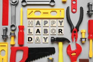 Oyuncak inşaat aletleri ve kelimeler gri arka planda mutlu LABOR Günü. İşçi Bayramı kutlamaları