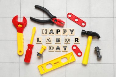 Oyuncak inşaat aletleri ve kelimeler beyaz fayanslı arka planda mutlu LABOR Günü. İşçi Bayramı kutlamaları