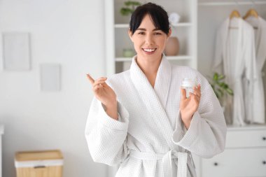 Krema kavanozlu, waffle bornozlu genç bir kadın.