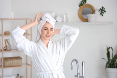 Duştan sonra evde bornozlu genç bir kadın var.