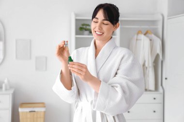 Waffle bornozlu genç bir kadın ve evde serum.