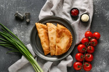 Gri grunge masasında lezzetli chebureks, sebze ve soslu tabak.