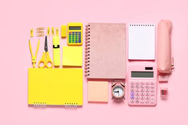 Pembe zemin üzerinde farklı okul kırtasiyesi, hesap makinesi ve alarm saati olan kompozisyon