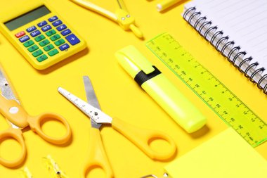 Hesap makinesiyle kompozisyon ve sarı arka planda farklı okul kırtasiyesi, yakın plan
