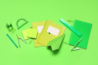 Kağıt uçak ve yeşil arka planda farklı okul kağıtları ile kompozisyon