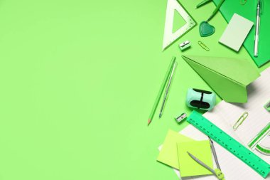 Yeşil zemin üzerinde kağıt uçak ve okul kırtasiyesi olan kompozisyon