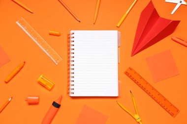 Boş defterden yapılmış çerçeve ve turuncu arka planda farklı okul sayfası, yakın plan
