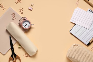 Bej arka planda farklı okul kırtasiyesinden ve alarm saatinden yapılmış çerçeve, yakın plan