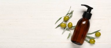 Hafif ahşap zemin üzerinde zeytin özü bulunan doğal kozmetik ürünü şişesi.