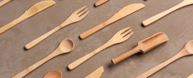 Kahverengi arka planda tahta çatallar, bıçaklar ve kaşıklar.