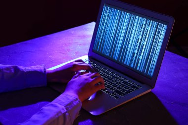 Kadın programcı gece ofiste dizüstü bilgisayarda daktilo kullanıyor.