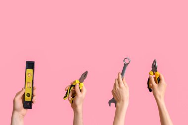 Electrician hands with tools on pink background