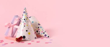 Parti şapkaları, hediye ve konfeti pembe arka planda mesaj için yer var.