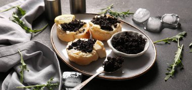 Koyu arkaplanda lezzetli siyah havyarlı ekmek dilimleri.