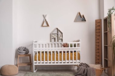 Çocuk odasının içinde beşik, raf ve oyuncaklar var.