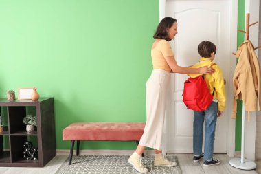 Anne oğlunu koridorda okula hazırlıyor.