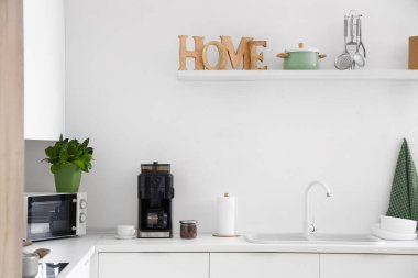 Beyaz tezgahta kahve makinesi olan modern mutfağın içi.