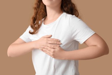 Bej arka planda göğüslerini kontrol eden genç bir kadın, yakın plan. Kanser farkındalığı kavramı