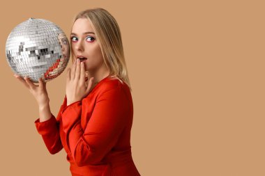 Kahverengi arka planda disko topu olan güzel, şok olmuş genç bir kadın.