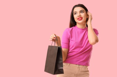 Pembe arka planda alışveriş çantası olan güzel bir genç kadın. Kara Cuma indirimi
