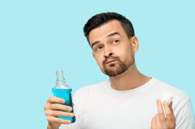 Mavi arka planda ağzını çalkalayan yakışıklı bir adam.