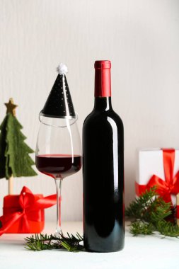 Beyaz arka planda Noel hediyesi kutuları olan bir şişe ve bir bardak şarap.