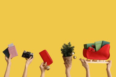 Pasaportları kameralı ve sarı arka planda Noel dekoru olan kadın eli. Yeni yıl tatili kavramı