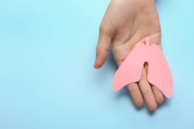 Mavi arka planda kağıt ciğerli bir kadın.