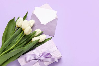 İçinde boş kart, hediye kutusu ve eflatun arkaplanda beyaz laleler olan zarf.