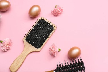 Çiçekli saç fırçaları ve pembe arka planda Paskalya yumurtaları.