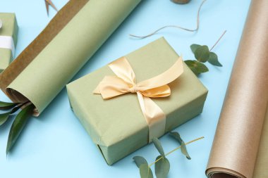 Paket kağıdıyla birlikte hediye kutusu ve mavi arka planda yapraklar. Uluslararası Kadınlar Günü