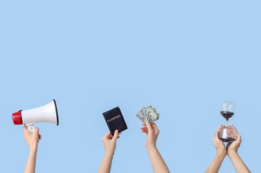 Kum saati, megafon, hukuk kitabı, pasaport ve mavi arka planda para tutan kadın elleri