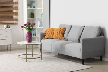 Masanın üzerinde güzel mor laleler olan modern oturma odası ve vazo.