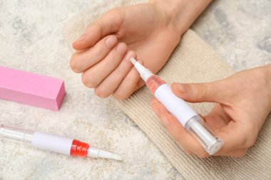 Hafif grunge arka planında tampon, havlu ve tırnak içi yağı kalemleri olan kadın eller