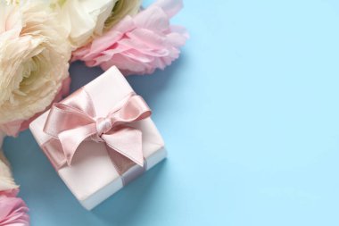 Mavi arka planda hediye kutusu olan güzel ranunculus çiçekleri