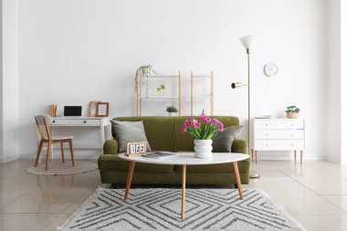 İçinde lale, dergi ve takvim olan vazo şık oturma odasının iç tarafında.